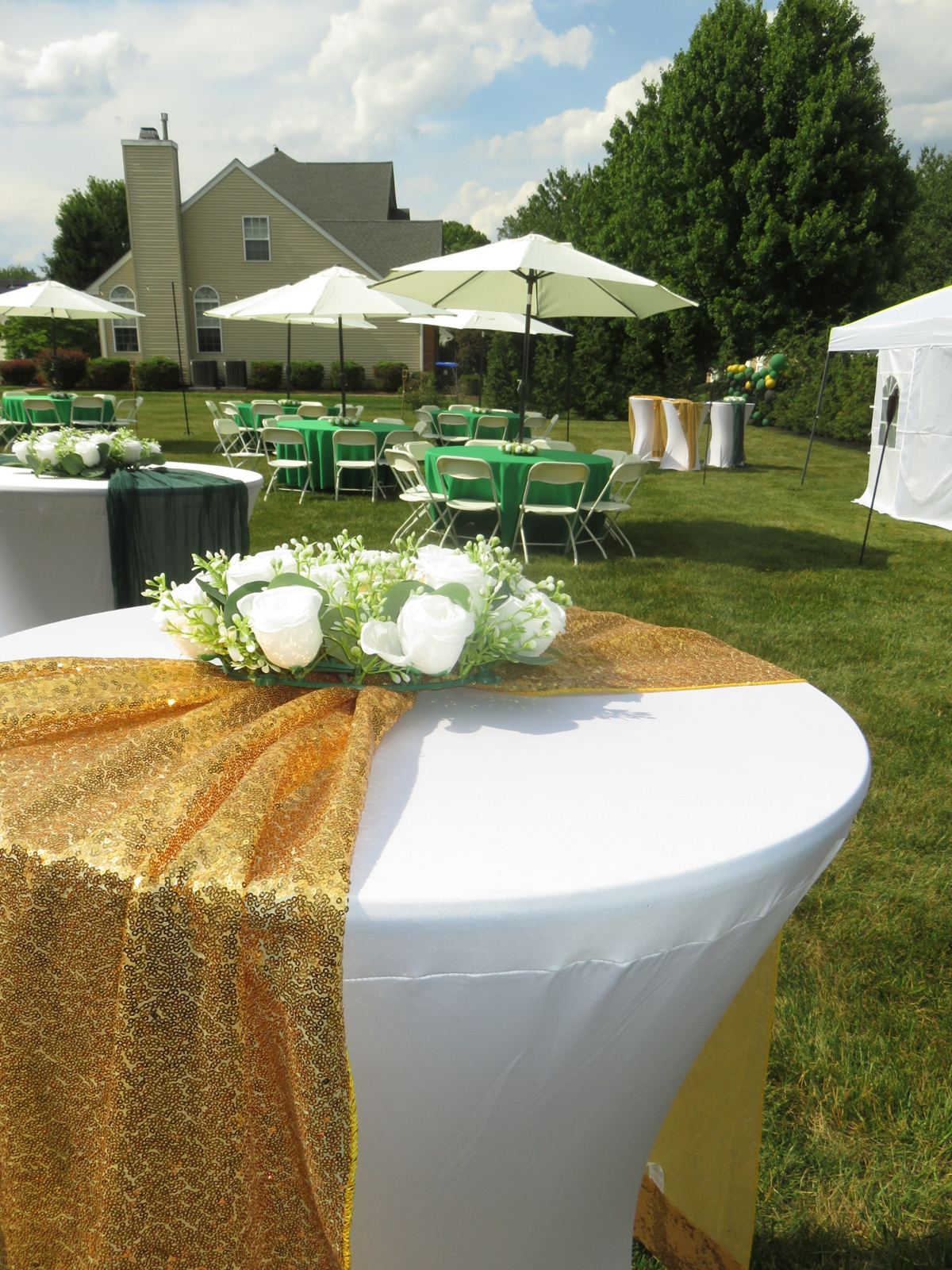 Cocktail table in a white spandex cover with a gold sequin runner and floral centerpiece