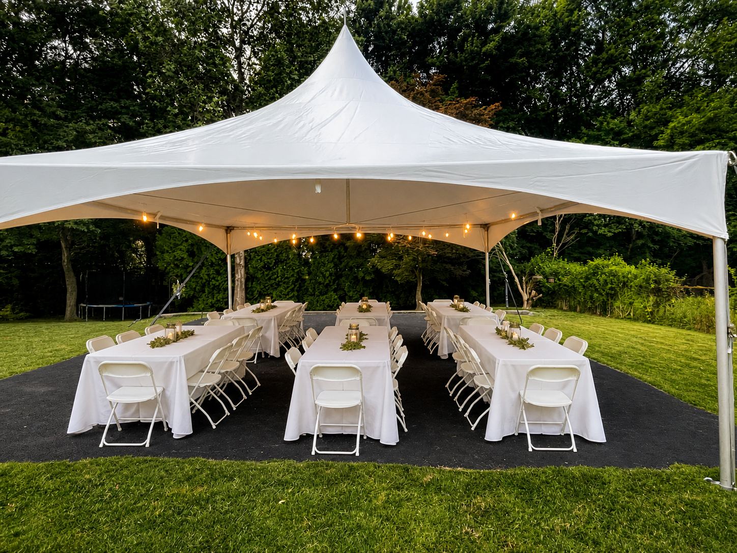 A 20×20 high-peak tent with string lights over long tables in white linens